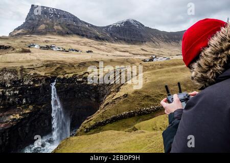 Pilote volant son drone (uav) au-dessus de la cascade de Mulafossur sur l'île de Vagar, dans les îles Féroé Banque D'Images