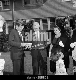 Week-end à Newport, Rhode Island : le président Kennedy est accueilli par James L. Maher, maire de Newport et sa femme. Le maire James L. Maher de Newport et son épouse Mary Maher présentent des cadeaux à la famille Kennedy à leur arrivée à Newport, Rhode Island. (G-D) le président John F. Kennedy; le maire Maher; Mme Maher; Caroline Kennedy; la première dame Jacqueline Kennedy (la plupart du temps hors du cadre). Banque D'Images