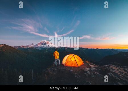 Un homme est debout près d'une tente au sommet d'une montagne près de mt. Rainier Banque D'Images