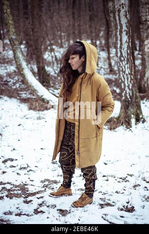 autre femme se tient dans la neige portant une veste de couleur moutarde Banque D'Images