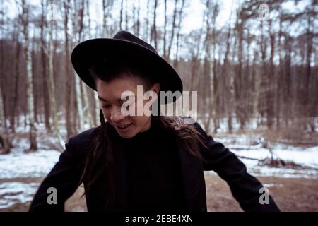 femme asiatique androgyne avec chapeau et veste noirs blanc froid Banque D'Images