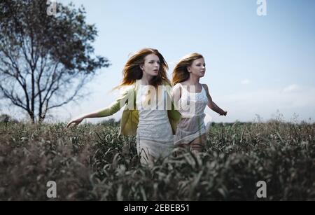 Deux femmes qui s'exécutent dans la prairie. Convient parfaitement à la couverture de livre Banque D'Images