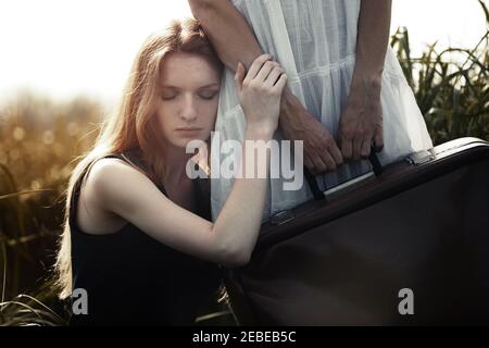 Triste femme penchée à la sœur tenant la valise. Convient parfaitement à la couverture de livre Banque D'Images