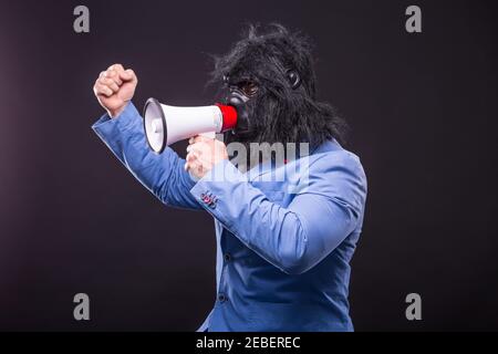 businessman wearing gorilla mask and screaming to megafon Banque D'Images