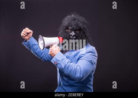 businessman wearing gorilla mask and screaming to megafon Banque D'Images