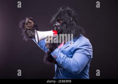 businessman wearing gorilla mask and screaming to megafon Banque D'Images