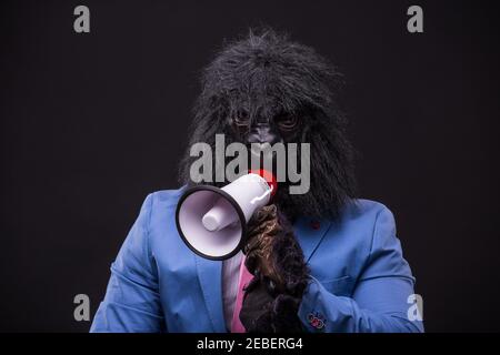 businessman wearing gorilla mask and screaming to megafon Banque D'Images