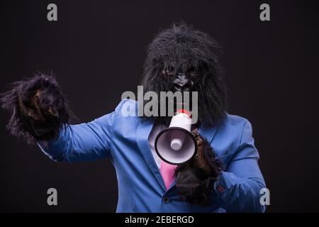 businessman wearing gorilla mask and screaming to megafon Banque D'Images