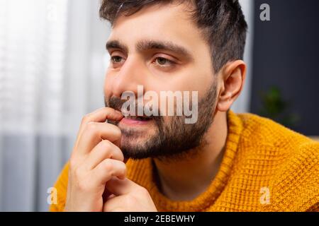 Portrait en gros plan d'un homme malheureux, un jeune homme d'affaires triste et réfléchi qui pense profondément, troublé par des erreurs, du doigt à la bouche, regardant Banque D'Images