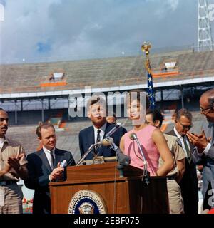 Discours devant la Brigade 2506 à Miami, 10:34AM. La première dame Jacqueline Kennedy fait des remarques en espagnol lors d'une cérémonie de présentation du 2506e drapeau de la brigade d'invasion cubaine au stade Orange Bowl à Miami, en Floride; les membres de la brigade ont présenté leur drapeau au président John F. Kennedy et à Mme Kennedy. Debout sur la plate-forme speakersu0027 (de gauche à droite): Erneido Oliva, deuxième commandant de la brigade (applaudissant); Maire de Miami, Robert King High (applaudissant); Président Kennedy; José Pu00e9rez San Romu00e1n, commandant de la brigade (à l'arrière, surtout caché); la première Dame (a Banque D'Images