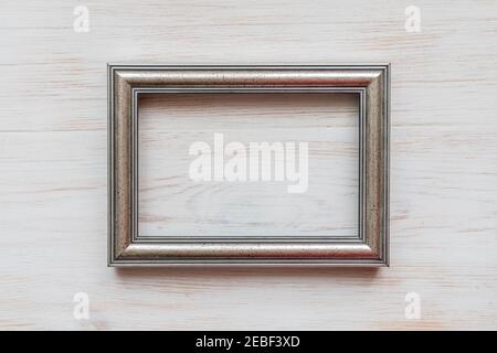 Cadre blanc argenté pour la peinture, l'image ou le texte sur fond de bois blanc. Cadre photo en bois vide utilisé pour les produits exposés isolés sur bac Banque D'Images