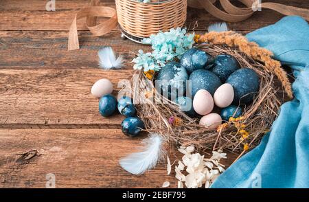 Joyeuses Pâques, fond festif avec des œufs dans un nid sur un fond en bois. Banque D'Images