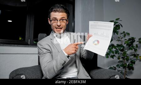 Homme d'affaires pointant du doigt sur les graphiques du document pendant la vidéo appeler Banque D'Images