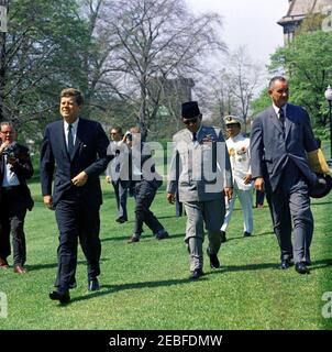 Cérémonies de départ pour Sukarno, Président de l'Indonésie, 10:40. Le président John F. Kennedy et le vice-président Lyndon B. Johnson marchent avec le président de l'Indonésie Ahmed Sukarno avant le départ du président Sukarnou2019s, South Lawn, White House, Washington, D.C. les membres de la presse suivent, y compris le photographe de presse pour United Press Movietone, Thomas J. Craven, Sr Banque D'Images