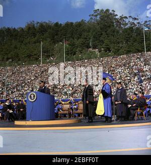 Voyage en Californie : cérémonie d'anniversaire de la Charte, Université de Californie à Berkeley, 13:40. Le président de l'Université de Californie, le Dr Clark Kerr (au lectern), prend la parole à la 94e cérémonie du jour de la Charte de l'Université de Californie, avant de présenter au président John F. Kennedy un doctorat honorifique en droit de l'Université de Californie. Le président Kennedy et le régent de l'Université de Californie, le Dr Edwin W. Pauley (en robe bleue), se trouvent à droite du Dr Kerr. Edward W. Strong, chancelier de l'Université de Californie de Berkeley, récemment inauguré, est assis à l'arrière-plan (entre Pres Banque D'Images