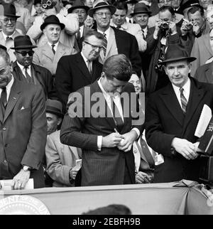 Jour d'ouverture de la saison de baseball 1961, 13:10. Le président John F. Kennedy signe un baseball au match d'ouverture de la saison de baseball 1961 au Griffith Stadium, Washington, D.C. l'audience comprend le vice-président Lyndon B. Johnson; le secrétaire de presse associé Andrew Hatcher; l'adjoint spécial du président Lawrence u0022Larryu0022 Ou0027Brien; le représentant Carl Albert de l'Oklahoma; Assistant spécial du président Dave Powers. Banque D'Images