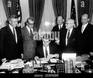 Signature de l'instrument de ratification pour l'adhésion des États-Unis à l'Organisation de coopération et de développement économiques (OCDE), 11:09. Signature de l'instrument de ratification de l'adhésion des États-Unis à l'Organisation de coopération économique u0026 développement (OCDE). Le président John F. Kennedy siège à son bureau. Debout (G-D): Le sénateur John J. Sparkman (Alabama); le sénateur Everett Dirksen (Illinois); le secrétaire au Trésor, C. Douglas Dillon; le sénateur Alexander Wiley (Wisconsin); le secrétaire d'État, Dean Rusk. Oval Office, Maison Blanche, Washington, D.C. Banque D'Images