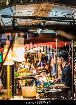 Un cuisinier prépare des plats à base de nouilles dans un plat au marché nocturne de Patong à Bangkok, en Thaïlande.