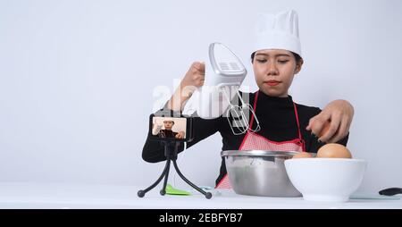Blogueur de nourriture. Asian femme chef streaming en direct. Elle communique avec les abonnés par téléphone caméra en ligne. Enregistreur de données et en ligne influenceur enregistrement Banque D'Images