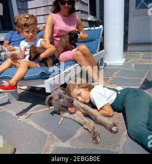 Voyage à Hyannis Port u2013 Squaw Island, 1963-08-14. Le président John F. Kennedy (partiellement caché), la première dame Jacqueline Kennedy, et leurs enfants, Caroline Kennedy et John F. Kennedy, Jr., sont assis avec leurs chiens, Wolf, White Tips, et Blackie, à la maison Brambletyde sur Squaw Island, Hyannis Port, Massachusetts. Banque D'Images