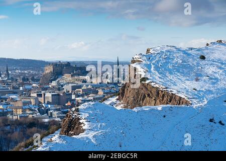 Vue sur les rochers de Salisbury couverts de neige en hiver dans Holyrood Park avec le château d'Édimbourg à l'arrière, Edimbourg, Écosse, Royaume-Uni Banque D'Images
