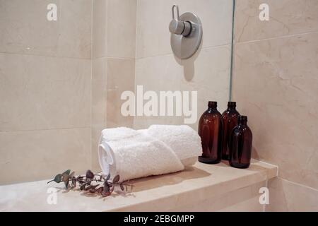Bouteilles de shampooing en verre ambré sans pompe dans un spa et une douche en marbre de luxe. Banque D'Images