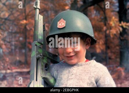 Week-end à Atoka, Virginie 1963-11-10 - 1962-11-11. John F. Kennedy, Jr., porte un casque et tient une mitrailleuse sur le terrain de la résidence de la famille Kennedy, Wexford, à Atoka, en Virginie. Banque D'Images