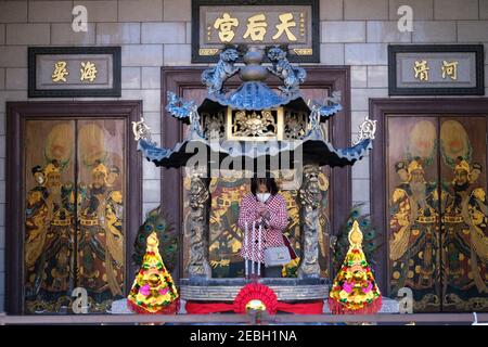 Los Angeles, Californie, États-Unis. 12 février 2021. Une femme portant un masque facial prie avec de l'encens au temple fermé de Thien Hau le premier jour du nouvel an lunaire chinois, l'année de l'Ox sur le zodiaque chinois, pendant la pandémie du coronavirus. Crédit: Ringo Chiu/ZUMA Wire/Alay Live News Banque D'Images