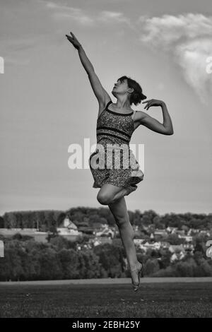 Belle danseuse jeune et élégante sautant dans le ciel, en noir et blanc Banque D'Images