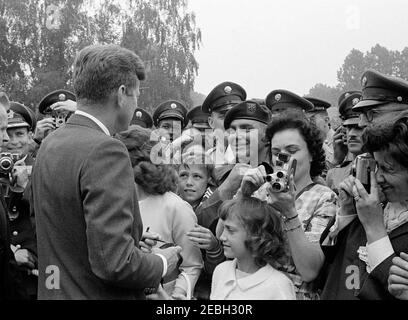 Voyage en Europe: Allemagne, Hanau: Départ de Fliegerhorst Kaserne, 14h00. Le président John F. Kennedy (à gauche, de retour à la caméra) accueille des foules rassemblées à Hanau, en Allemagne de l'Ouest (République fédérale), lors de sa visite à la base militaire de Fliegerhorst Kaserne. Banque D'Images