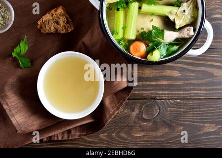 Bouillon de poulet avec légumes et épices sur fond de bois. Vue de dessus, plan d'appartement Banque D'Images