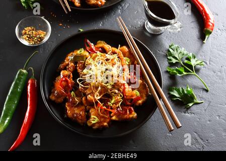 Poulet frit à l'ail épicé (Kkanpunggi). Poulet asiatique en sauce aigre-douce sur plaque sur fond de pierre noire. Banque D'Images