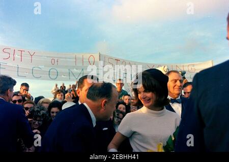 Voyage au Texas : Houston : arrivée à l'aéroport international de Houston. Le président John F. Kennedy (à l'extrême gauche, avec de retour à la caméra) accueille les gens dans la foule alors que la première dame Jacqueline Kennedy (à droite) parle à un homme non identifié à l'aéroport international de Houston, au Texas. Le représentant Albert Thomas (Texas) est à droite de la première dame. Banque D'Images