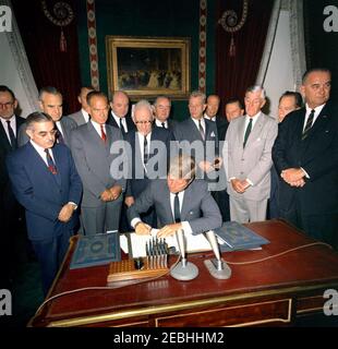 Cérémonie de signature, Traité d'interdiction des essais nucléaires, 10 h 00. Le Président John F. Kennedy signe le Traité d'interdiction des essais nucléaires dans la salle des traités de la Maison Blanche, Washington, D.C., à l'étude (L-R) : Directeur adjoint de l'Agence de contrôle des armements et du désarmement (ACDA), Adrian S. Fisher; le sénateur John O. Pastore (Rhode Island); Le sous-secrétaire d'État aux Affaires politiques, W. Averell Harriman; le sénateur George A. Smathers de la Floride (surtout caché); le sénateur J. William Fulbright (Arkansas); le secrétaire d'État, Dean Rusk; le sénateur George D. Aiken (Vermont); le sénateur Hubert H. Humphrey (Minnesota); le sénateur Everett M. Banque D'Images