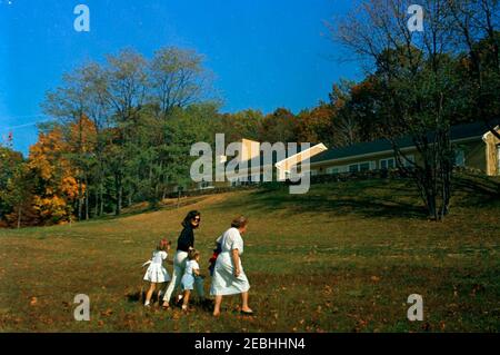 Week-end à Atoka : Jacqueline Kennedy (JBK), Caroline Kennedy (CBK), John F. Kennedy Jr. (JFK, Jr.) et l'infirmière Maud Shaw arrivent par hélicoptère. La première dame Jacqueline Kennedy, Caroline Kennedy, et John F. Kennedy, Jr., arrivent à la résidence familiale Kennedy, Wexford, à Atoka, en Virginie. Nanny aux enfants Kennedy, Maud Shaw, marche à droite. Banque D'Images