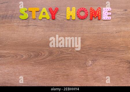 Inscription de lettres en bois RESTER À LA MAISON sur fond de bois avec espace de copie. Titre RESTEZ À LA MAISON sur fond de bois pour le maquillage. Vue de dessus. Promotion de la conception Banque D'Images