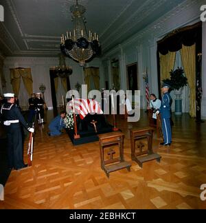 Funérailles d'État du président Kennedy : couché en repos dans la salle est de la Maison Blanche. Feu le président John F. Kennedy se trouve dans la salle est de la Maison Blanche. L'aide de la Force aérienne au président Kennedy, le général de brigade Godfrey T. McHugh, dépose une couronne sur le cercueil à pavillon du Presidentu2019s. Les membres de la garde d'honneur tiennent la montre. Washington, D.C. Banque D'Images