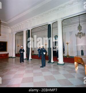 Funérailles d'État du président Kennedy : départ de la Maison Blanche et procession au Capitole des États-Unis. Vue sur le hall d'entrée et le Cross Hall, drapés en crêpe noire de deuil pour les funérailles d'État du Président John F. Kennedy. Les membres de la garde d'honneur sont à l'attention. White House, Washington, D.C. Banque D'Images