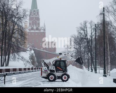 Moscou. Russie. 12 février 2021. Un petit bobcat de pelle-chargeuse enlève la neige du trottoir près des murs du Kremlin lors d'une forte chute de neige Banque D'Images