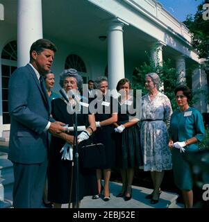 Visite des membres de la u0022Ninety-Nines,u0022 une association de pilotes féminins, 9:45. Le président John F. Kennedy fait des remarques aux membres de la Ninety-Nines, Inc., Organisation internationale des femmes pilotes, au cours d'une visite au sujet de l'émission d'un timbre commémoratif Amelia Earhart. De gauche à droite: Président Kennedy; président international, Louise M. Smith (en arrière); ancien président international, Blanche Noyes; Alice Hammond; Marion Andrews-Lopez; Fay Gillis Wells; non identifié. Ken Giannoules, agent du service secret de la Maison Blanche, est en colonnade en arrière-plan. Jardin de roses, blanc Banque D'Images