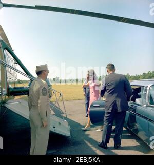 Voyage à Hyannis Port u2013 Squaw Island, 1963-08-14. La première dame Jacqueline Kennedy se prépare à monter à bord d'un hélicoptère au cours d'une visite à Squaw Island; le président John F. Kennedy (pour la plupart caché) quitte la voiture. Port de Hyannis, Massachusetts. Banque D'Images