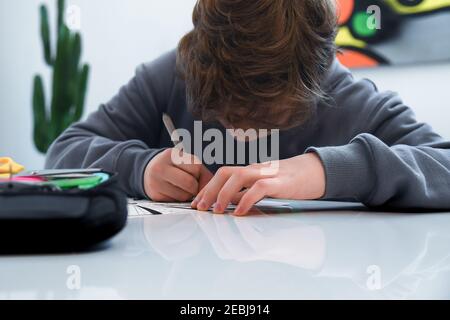 L'adolescent dessinant seul à la maison pendant le verrouillage du Covid-19. Un jeune garçon caucasien fait des travaux à domicile. Apprentissage des élèves en période de pandémie étude des enfants à l'école à domicile Banque D'Images
