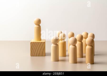 Figure de leader se tenant à l'extérieur de la foule sur cube en bois, d'autres figures autour sur le plancher. Leadership et équipe. Patron et subordonnés. Individualité et sup Banque D'Images