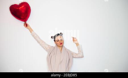 Une femme avec ses yeux fermés laisse un ballon d'amour la porter. Espace négatif ou espace de copie pour le texte. Banque D'Images