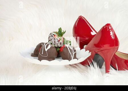 fraises enrobées de chocolat sur un plat sur socle en fourrure blanche avec pompes rouges Banque D'Images