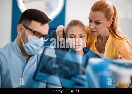 Famille dans le cabinet du dentiste.dentiste en interaction avec la mère et la fille pendant l'examen dentaire à la clinique. Banque D'Images