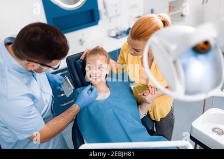Famille dans le cabinet du dentiste.dentiste en interaction avec la mère et la fille pendant l'examen dentaire à la clinique. Banque D'Images