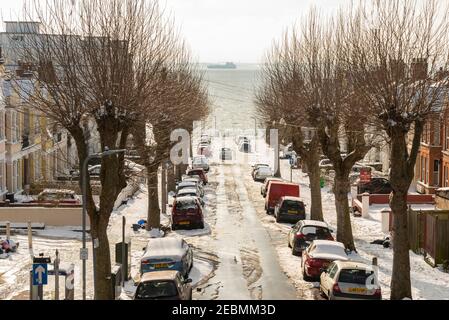 Rue de Westcliff on Sea, Southend, Essex, Royaume-Uni, en direction de l'estuaire de la Tamise, avec de la neige sur le sol depuis Storm Darcy. Route côtière bordée d'arbres Banque D'Images