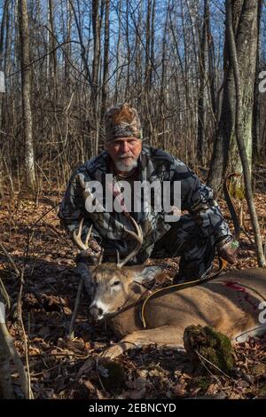 Hunter pose avec son arc et sa flèche récursive sur mesure et son buck récolté dans le nord du Wisconsin. Banque D'Images