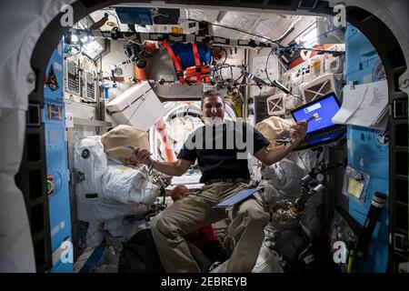 L'astronaute de la NASA et l'ingénieur de vol de l'expédition 64 Michael Hopkins inspectent le matériel de sortie de l'espace à l'intérieur de l'écluse Quest où les sorties de l'espace aux États-Unis sont entreposées à bord de la Station spatiale internationale le 8 janvier 2021 à Earth Orbit. Banque D'Images